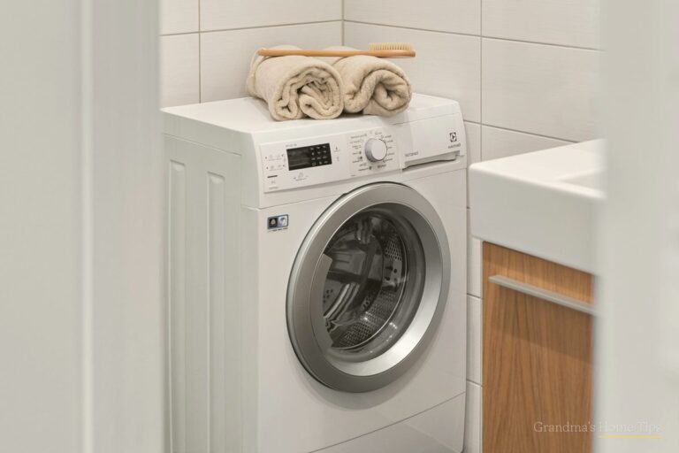 Clean laundry room with a white front-load washing machine and folded towels